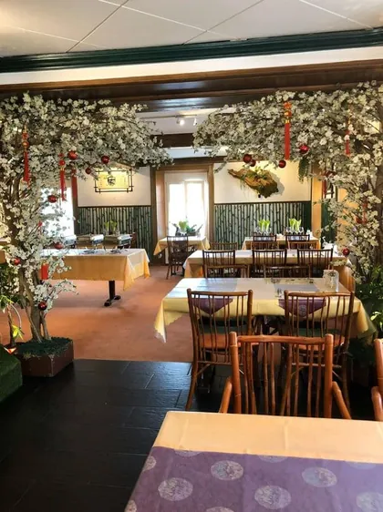 La salle aux cerisiers : deux arches de fleurs, des lampions, des tables nappées et des chaises de bambou